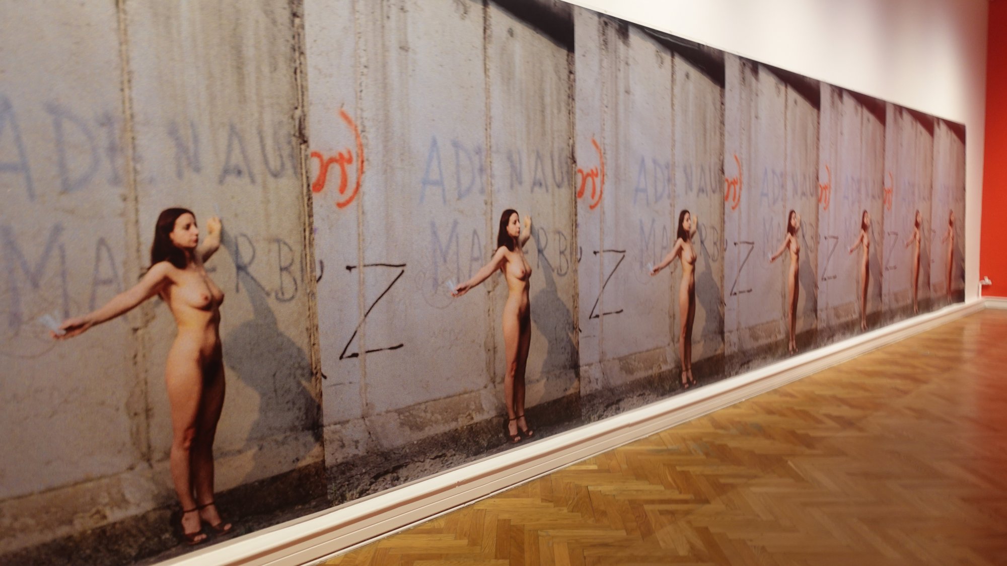 Kunstinstallation mit großformatigem Foto einer Frau vor einer Betonmauer mit Graffiti.